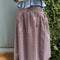 back view of model wearing brown striped midi skirt with asymmetrical detail on the waist
