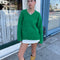 model wearing green textured v-neck sweater and twill skirt
