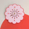 light pink retro daisy shaped clock with mauve trim