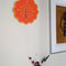orange retro floral clock with yellow trim on a wall
