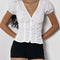 up close of model wearing white cotton short sleeve blouse with deep v-neck, button front and corset waist and black shorts