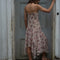 back view of model wearing pink floral midi dress with layered hem, bow detail and v-neckline