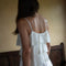 back view of model wearing white tiered lacy tank with matching skirt