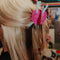 model wearing pink ball of yarn hair claw with two mint knitting needles sticking out.