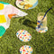 cream set of 4 coasters with colorful all over geometric shapes with a drink on it in the grass