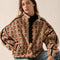 model wearing tan fleece half zip sweatshirt with red floral print and black piping on the arms and zipper