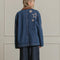 back view of model wearing denim oversized jacket with corduroy collar, patch pockets, and embroidered star, moon and sun pattern