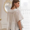 back view of model wearing white lace collar blouse with slight puffy sleeves, faux button down front and dainty black polka dots