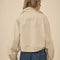 back view of model wearing light khaki cropped jacket with stand up collar and elastic bottom