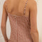 up close of back view of model wearing brown and white gingham cotton midi dress with spaghetti straps and drop waist