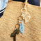 blue surfboard key charm with gold hardware on a raffia bag