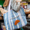 model carrying blue and lavender plaid recycled plastic tote with ribbon detail and crescent applique