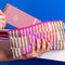 model putting a notebook in puffy colorful multi-stripe pencil pouch