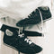 model carrying black vans super low pro trainer sneakers with white laces