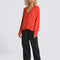 model wearing red boucle relaxed fit cardigan and black pants