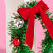 side view of green tinsel headband with red velvet bow and ornaments