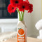 orange juice vase on wooden table with red gerbera daisies