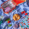 strawberry print lunch box shown with food and beverage cans on blue gingham backdrop