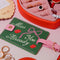 green luggage tag with pink strap and trim with 'miss you already' in cursive surrounded by cute items