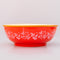 side view of red large ceramic serving bowl with light pink garden border and orange rim with green veggie inside