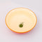 top view of cream interior of red large ceramic serving bowl with light pink garden border and orange rim with green veggie inside