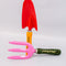 scattered set of two metal gardening tools: red and yellow 'plant parent' towel and pink and green 'plant parent' trident