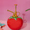 ceramic tomato plant mister with gold pump on a pink ground
