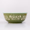 side view of green small ceramic serving bowl with orange interior and red strawberry stamp inside and light blue trim