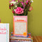 pink word search puzzle book shaped ceramic vase on a stack of ban.do planners