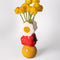 stacked vase with white flower, an apple on it's side and smiley face with flowers inside with flowers inside