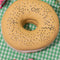 everything bagel shaped de-stress ball laying on a gingham print table