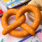soft pretzel shaped de-stress ball with white heart shaped 'salt' on top on a desk