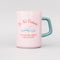front view of light pink ceramic mug with teal handle and 'do not disturb! i am currently reading a really good book!' typography on both sides