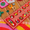 up close of red and cream gingham mancala board with colorful fruit game pieces on a table