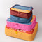 Set of four colorful packing cubes with different printed phrases, shown stacked together.