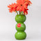 three green olives stacked vase with gerber daisies inside