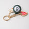fidget keychain with gold heart photo frame, enamel orange juice charm, and 8-ball de-stress ball