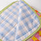 light blue and white gingham underside of colorful patchwork print quilted blanket  with light green trim