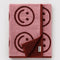 folded pink and maroon reversible smiley towel