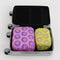 set of 2 packing cubes: small yellow with hot pink smiley print and medium pink with cobalt smiley print in a suitcase