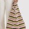 model holding pink and yellow horizontal gradient stripe baggu