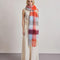 model wearing thick scarf with various shades of blue  and red checkers and fringe