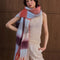 model wearing thick scarf with various shades of blue  and red checkers and fringe