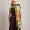 model wearing thick scarf with orange, burnt red, and moss green print and fringe