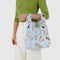 model holding light blue baby baggu with various hair, makeup and floral print