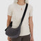 model wearing black washed denim small crescent bag with black adjustable strap