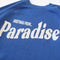 up close of blue sweatshirt with white 'GREETING FROM...PARADISE' across the front
