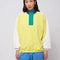 model wearing relaxed fit color block sweatshirt with yellow body, white sleeves, teal zipper placket and navy collar