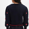 back view of model wearing black cropped cardigan with red folk floral print on the front and sleeves