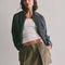 model wearing olive green mini skirt with pleated front and raw hem